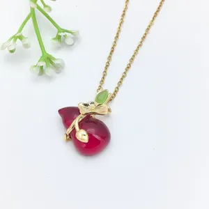 Primo piano della collana con pendente a zucca rossa, elegante gioiello con catena d'oro.