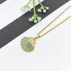 Primo piano della collana con ciondolo a conchiglia dorata con pietre blu e dettagli di catena.