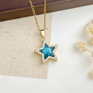 Dettaglio di una collana con ciondolo a stella dorata, cristallo blu e pavé di zirconi.