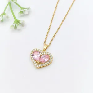 Dettaglio ravvicinato di una squisita collana con ciondolo a cuore dorato e zirconi rosa.
