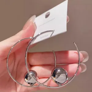 Vista dettagliata di orecchini a cerchio in argento con ciondolo a sfera, gioielli alla moda.