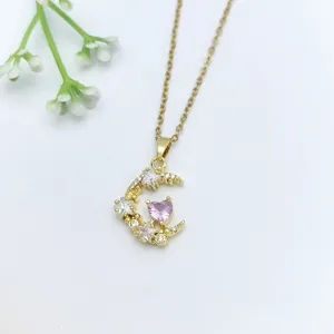 Collana con ciondolo luna e cuore dorata con zircone cubico brillante, primo piano.