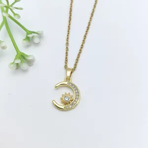 Dettaglio collana con ciondolo sole e luna dorata con zirconi micro-incastonati e catena sottile.