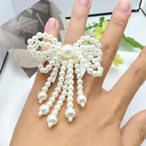 Primo piano di un elegante anello con fiocco di perle e fili pendenti per donna.