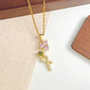 Collana in acciaio inossidabile dorato con delicato ciondolo fiore in zirconia rosa e verde.