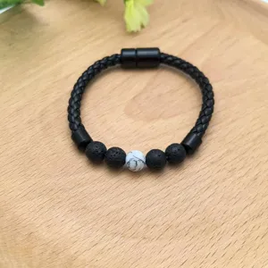 Dettaglio del bracciale in pelle intrecciata con chiusura magnetica e perle laviche.