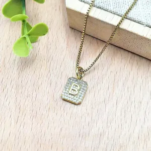 Primo piano della collana con ciondolo quadrato dorato, zirconi e lettera B.