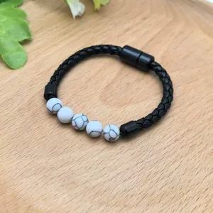Primo piano del bracciale in pelle nera intrecciata con perline bianche e chiusura magnetica.