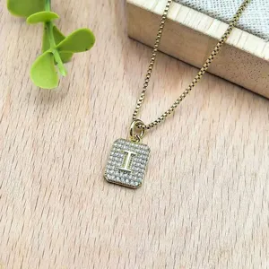 Primo piano dettagliato della collana con ciondolo a lettera in zircone dorato su legno.