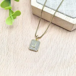 Primo piano dettagliato della collana con ciondolo lettera J in zircone su supporto in legno.