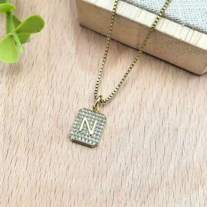 Dettaglio in primo piano di una collana con ciondolo lettera N in zircone quadrato dorato.