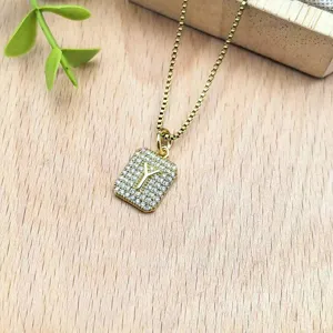 Primo piano della collana con ciondolo quadrato dorato con zirconi brillanti e lettera Y.
