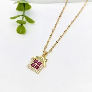 Primo piano della collana con ciondolo a forma di casa dorata, cristalli e pietre rosse.