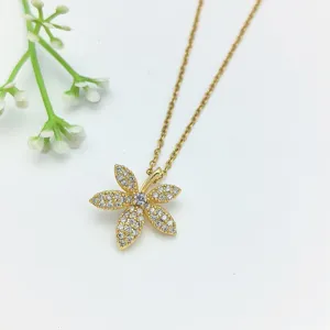 Dettaglio collana con ciondolo a fiore dorato, zirconi cubici scintillanti su catenina fine.