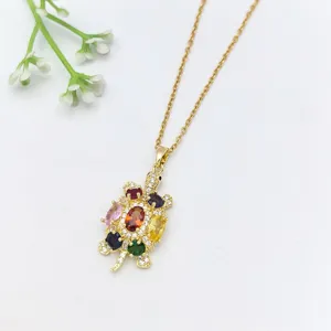 Dettaglio di una collana in acciaio dorato con ciondolo tartaruga in zircone multicolore.