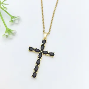 Primo piano della collana con ciondolo a croce dorata con zirconi neri scintillanti a goccia.