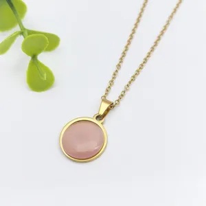 Primo piano di una delicata collana a catena dorata con pendente in resina rosa.