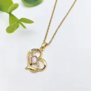 Dettaglio di collana con ciondolo a cuore in acciaio dorato e pietra zircone rosa.