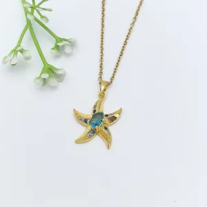 Primo piano della collana con ciondolo a stella Marina dorata con pietra blu e dettagli in zircone.