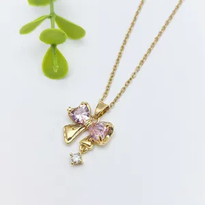 Primo piano di collana catena d'oro con ciondolo a fiocco in cristallo di cuore rosa.