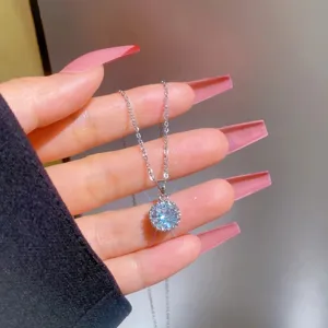 Primo piano dettagliato di una collana con ciondolo in zircone rotondo su catena in acciaio.