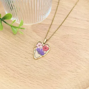 Primo piano di una collana vintage con ciondolo a cuore in resina e fiori.