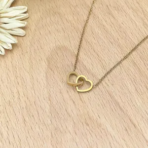 Close-up shot of an elegant gold interlocking double heart pendant necklace on wooden background.