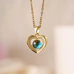 Primo piano della collana con ciondolo a cuore dorato e pietre micro-pavè brillanti.