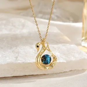 Primo piano dell'elegante collana con ciondolo a cigno d'oro con perla galassia stellata.