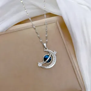 Primo piano dettagliato di una collana con ciondolo a forma di pianeta e luna crescente.