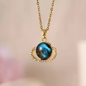 Dettaglio in primo piano della collana con ciondolo pianeta cielo stellato e cristalli brillanti.