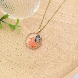 Dettaglio collana con pendente in resina e fiori secchi, accessorio catena clavicolare in acciaio.