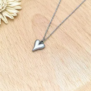 Stainless steel puffy heart pendant necklace detail shot, minimalist geometric jewelry.