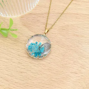 Dettaglio della collana in acciaio inossidabile con pendente in resina blu e fiori.