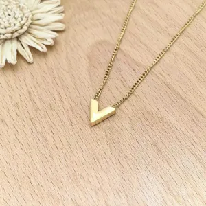 Detailed close-up view of a minimalist gold V-shaped pendant necklace on wooden backdrop.