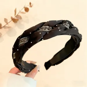 Primo piano dettagliato del cerchietto intrecciato in velluto nero con strass brillanti.