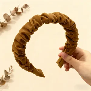 Primo piano del cerchietto in velluto marrone arricciato, con morbida trama e design intrecciato.