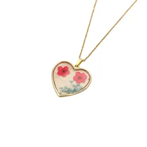 Collana con ciondolo a cuore dorato e veri fiori secchi in resina trasparente da donna.