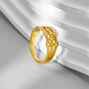 Dettaglio di un anello alla moda in acciaio inossidabile dorato, multi-fascia traforato con pietre.