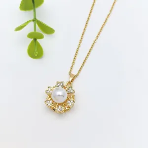 Exquisite detail view of a gold-toned rotating heart flower pendant necklace with a pearl.