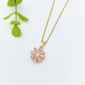 Detail shot of a gold flower necklace pendant featuring sparkling pink crystal stones.