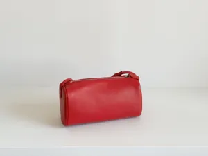 Vue détaillée du sac cylindrique minimaliste en cuir rouge, montrant la texture.