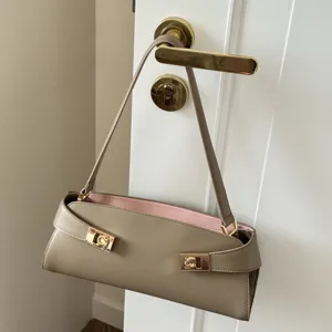 Stylish leather baguette shoulder bag for women, chic taupe underarm purse with pink lining.