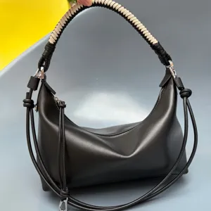 Detail shot of black leather dumpling shoulder bag featuring unique woven handle and metal hardware.