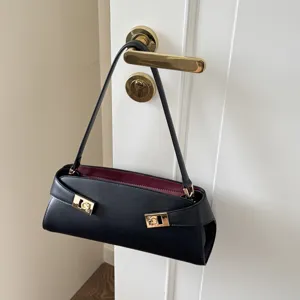 Black leather baguette shoulder bag with gold-tone hardware and elegant burgundy inner lining.