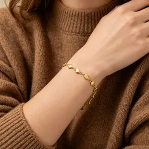 Close-up detail of 18k gold plated heart chain bracelet on wrist, elegant feminine jewelry.