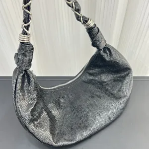 Black leather crescent shoulder bag with chain strap and stylish half moon design detail.