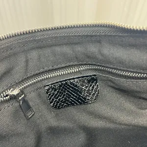 Detailed view of the black leather bag interior with zipper pocket and lining texture.