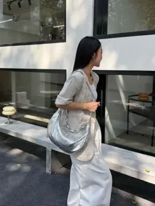 Silver metallic leather crescent shoulder bag, detailed view of the stylish underarm half-moon bag.