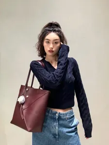 Vue détaillée d'un sac cabas géométrique pliable bordeaux porté avec un pull en maille.
